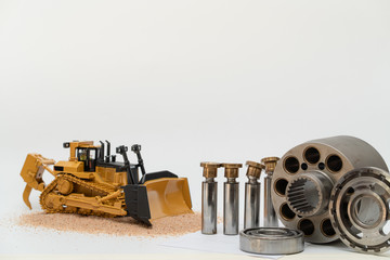 hydraulic piston pump parts with bulldozer tractor model on white background, repair maintenance heavy machinery concept