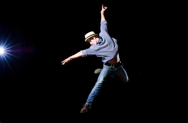 Modern ballet style male dancer performs on high lighted stage .