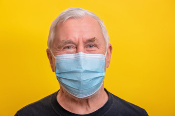 Senior man in medicine mask over yellow background with copy space