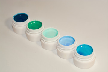 On white background cans with different shades of blue color with paints, varnishes for manicure.