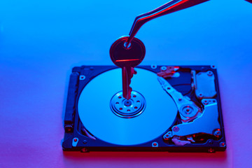 Data security concept. Key on spindle of a hard disk drive. Opened Hard disk.