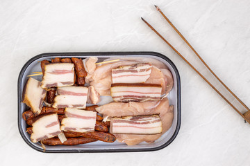 Top view of mixed meat prepared for grill. Bacon kebabs sausages and chicken breasts.