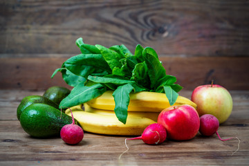 avocados, bananas, apples and radishes on a wooden table