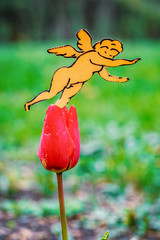 A paper-cut cupid sits on a tulip