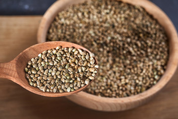 hemp seeds and a wooden spoon on a dark table. Wooden bowl on Cutting board. Healthy food concept.