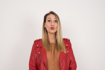 Attractive light haired female rounds lips, wears casual clothes, looks directly into camera, expresses her satisfaction, isolated over gray background. People, body language concept.