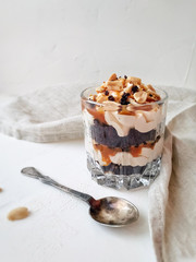 Chocolate dessert with salted caramel and peanuts in a glass close-up on a light background.