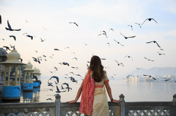A woman wearing saree is watching the sunrise and flying birds in Udaipur the most romantic place...