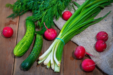 Fresh vegetables, cucumber, radish, onion and dill on a wooden table