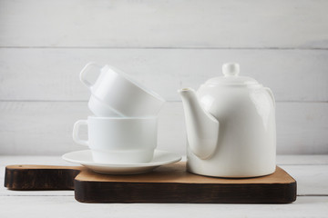 Fototapeta na wymiar Cup of tea, teapot, oak cutting board on white wooden background. Rustic style concept