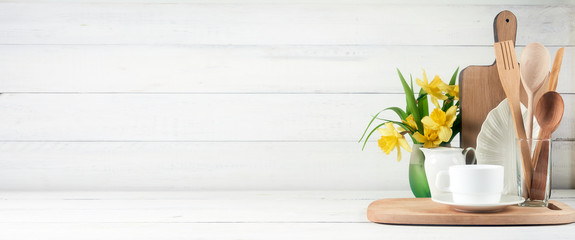 Kitchen wide banner concept. Kitchen background for mockup with spoon, teapot, cups, bowls, flowers on wooden table .