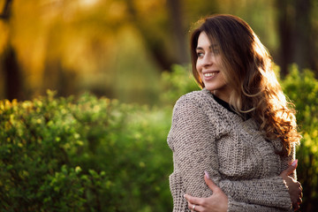 beautiful girl in park in knitted sweater smiling