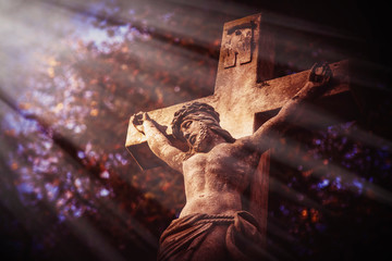 Ancient stone statue of the crucifixion of Jesus Christ in the sun's rays. Faith, religion,...