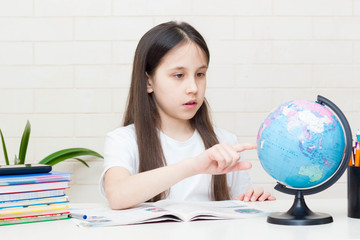 Distance learning online education. A schoolgirl is studying at home and doing homework. Sitting at the table with textbooks