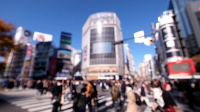 Blurred and unrecognizable people crossing the street at Shibuya intersection in the morning.	