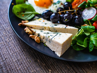 Continental breakfast - sunny side up egg, blue cheese, grapes and vegetable salad

