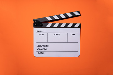 movie clapper on orange table background ; film, cinema and video photography concept
