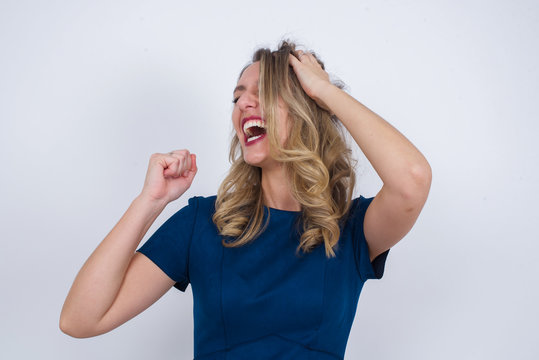Shot of happy young woman with positive smile, has long hair, rejoices having weekend and good rest after hard working exhausting week, isolated on gray wall. - Powered by Adobe