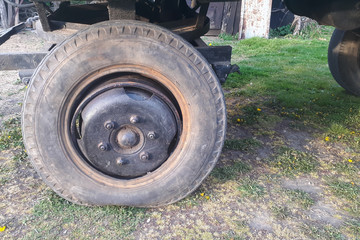 Fototapeta na wymiar Damaged old tire on the farm trailer. Breakdown and problems on the farm.