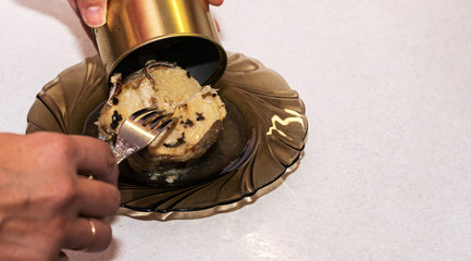 Women's hands open a tin of tuna.