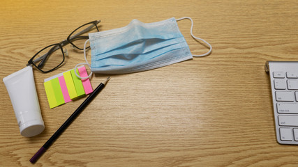 Top view of computer keyboard,  black pencil, eyeglassese, alcohal gel, and colorful paper postit on workspce brown wooden table.  for work from home or WFH

