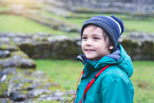 Portrait Of School Kid Explore And Learning About History With School Trip, Happy Child Boy Wearing Hat And Winter Cloths Standing Alone With Blurry Ruins Of Old Abbey Background