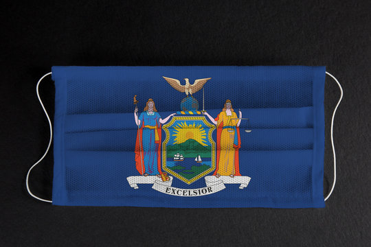 Coronavirus Covid-19 in New York. Flag of the State of New York printed on medical mask on black background. Coronavirus update in NY.  State healthcare concept.