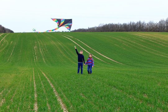 Children launch a kite in a field in spring