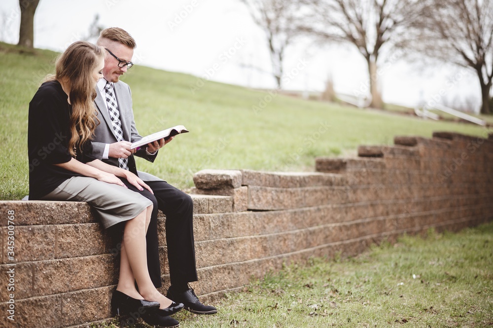 Wall mural view of a couple wearing formal clothes while reading a book together in a garden