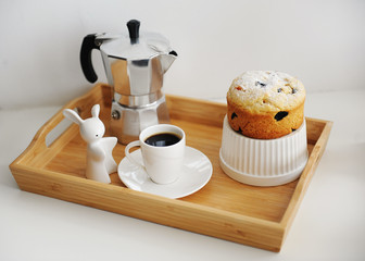 Coffee and cupcake served in wooden bamboo tray. Coffee maker moka pot, white dishes.