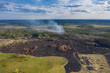 Field and forest after wildfires. The forest is still in smoke. Natural disasters or arson in April...