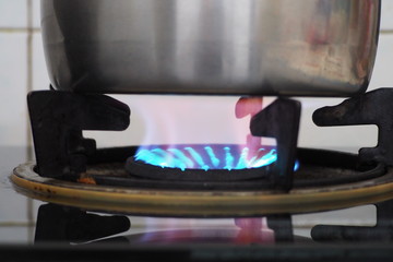 Closeup of hot blue flame from the old and local gas stove used to boil water for cooking in the kitchen. Gas and fuel usage in household consumption concept