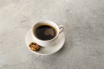 black coffee in a white cup with cookies on a gray background
