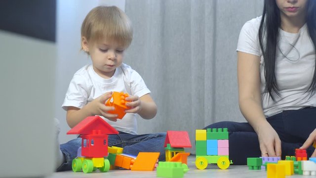 childhood happy family mom and children are playing concept little girl and boy brother and sister collects constructor teamwork. child plays toys sitting on floor. children play lifestyle in team