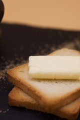White coffee and toast with butter and sugar. Breakfast in black tray on orange background. Cappuccino.