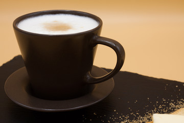 White coffee and toast with butter and sugar. Breakfast in black tray on orange background. Cappuccino.