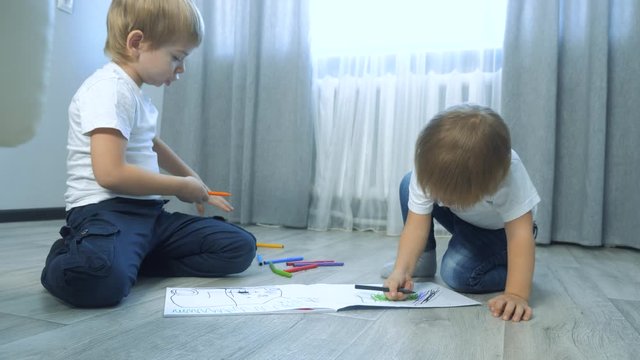 children draw with felt-tip pens in an album. little boy and girl concept childhood brother and sister lifestyle play paint on the floor with colored markers