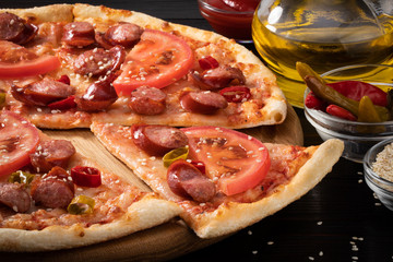 pizza with bavarian sausages, tomato and chili pepper on dark background