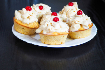 Obraz na płótnie Canvas six gluten-free corn and rice flour muffins with mascarpone cream and currant filling on a white plate on a dark background