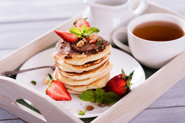 Pancakes  with chocolate sauce and fresh  strawberries on white wooden background. Delicious sweet dessert.