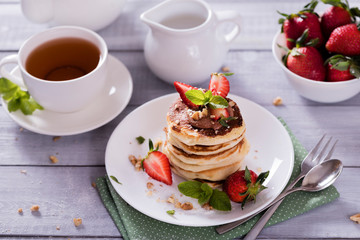 Pancakes  with chocolate sauce and fresh  strawberries on white wooden background. Delicious sweet dessert.