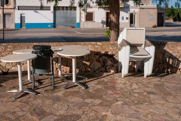 White plastic chairs stacked next to outdoor tables