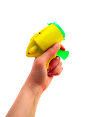 A hand, holding a yellow and green popper party confetti bullet gun, isolated on white. - 345303996