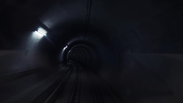 Dark underground subway tunnel with lanterns on the walls. Modern city transport.