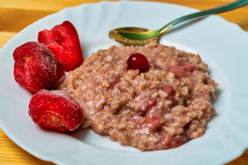 plate with oatmeal with strawberries on a wooden table