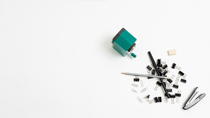 stapler, eraser, sharpener, bunch of black binder paper clips for documents, pencils randomly scattered in heap on white background. stationery isolated flat lay. top view of various office equipment