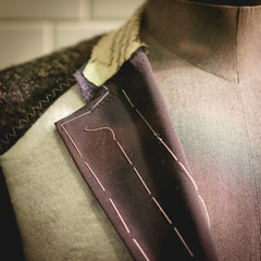 Detail of a clothing mannequin in a men suit shop with a white brick wall on the background. Elegance concept. Square format.