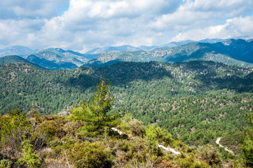 Fototapeta na wymiar Light clouds cast fancy shadows on the peaks and slopes of the Troodos Mountains. Shadows creep from mountain to mountain, changing their shape. 
