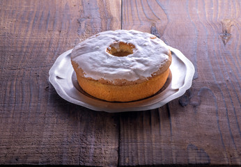 Homemade cake covered with powdered sugar on wooden background
