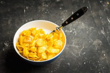 Tasty crispy corn flakes with milk in bowl on the rustic background. Selective focus. Shallow depth of field.